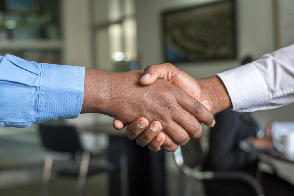 Dos personas estrechando la mano, representando colaboración entre entidades y acompañamiento social.
